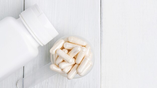 Weiße Pillen oder Kapseln in einem Plastiklöffel, medikamentöse Behandlung, Alternativmedizin, Nahaufnahme, Draufsicht