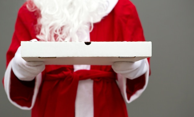 Weiße Pizzaschachtel in den Händen des Weihnachtsmannes in weißen Handschuhen