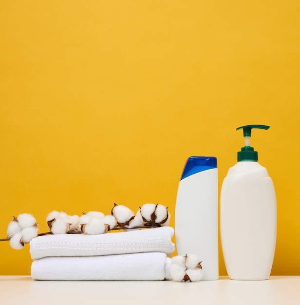 Weiße Plastikflaschen für Gel und Shampoo und gerollte weiße Frotteehandtücher