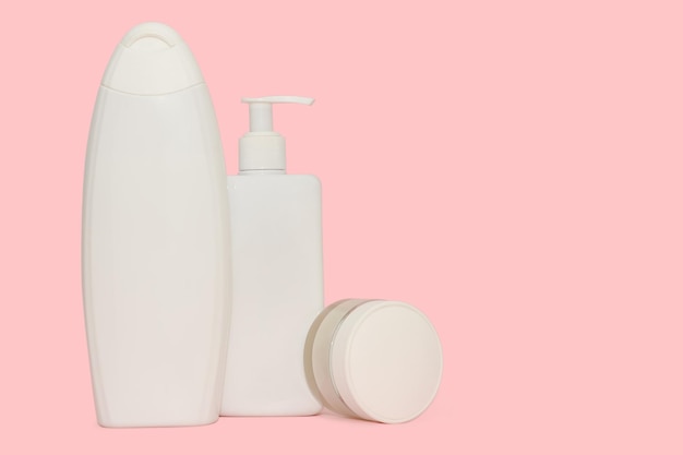 Weiße Plastikflaschen für Kosmetikprodukte auf rosa Hintergrund