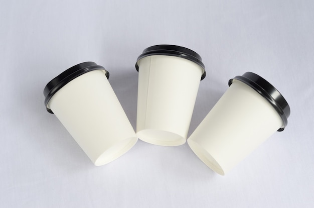 weiße Plastikkaffeetasse mit schwarzer Kappe auf Weiß