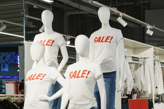 Weiße Plastikmannequins in einem weißen T-Shirt mit Prozentzeichen und Jeans