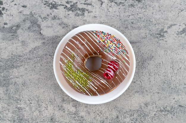 Weiße Platte des schokoladenglasierten Donuts auf Steinhintergrund.