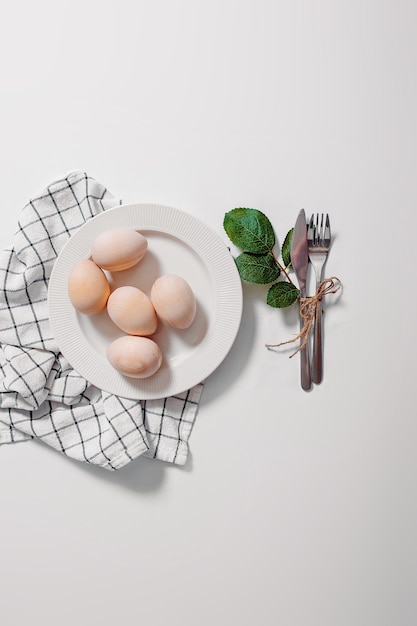 Foto weiße platte mit eiern auf weißem hintergrund frohe ostern-karte mit platte mit eiern und grünen blättern