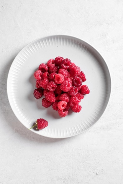 Weiße Platte mit frischen Himbeeren. Essen von oben.