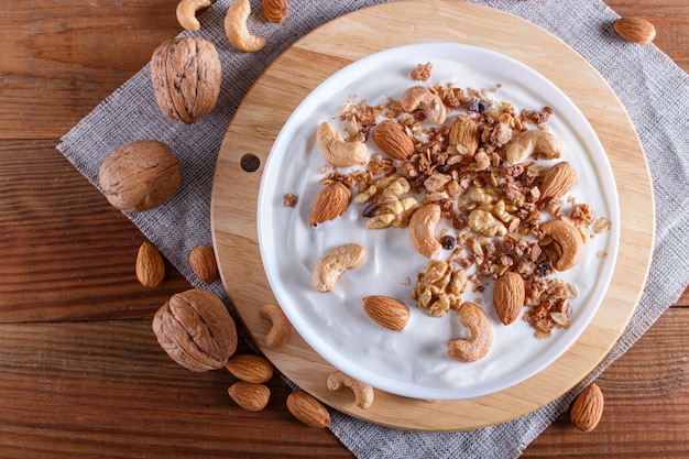 Weiße Platte mit griechischem Joghurt, Granola, Mandel, Acajoubaum, Walnüssen