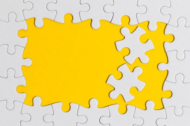 Weiße Puzzleteile auf gelbem Hintergrund Geschäftslösungskonzept