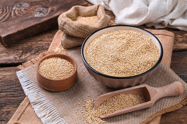 Weiße Quinoa-Samen in einer Schüssel auf braunem Holzhintergrund Seitenansicht Kopierraum