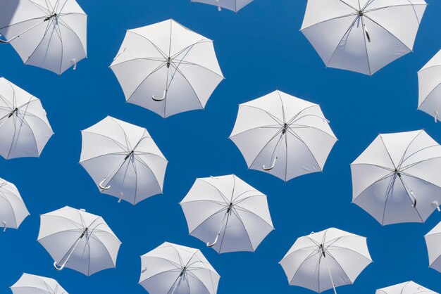 Weiße Regenschirme am blauen Himmel