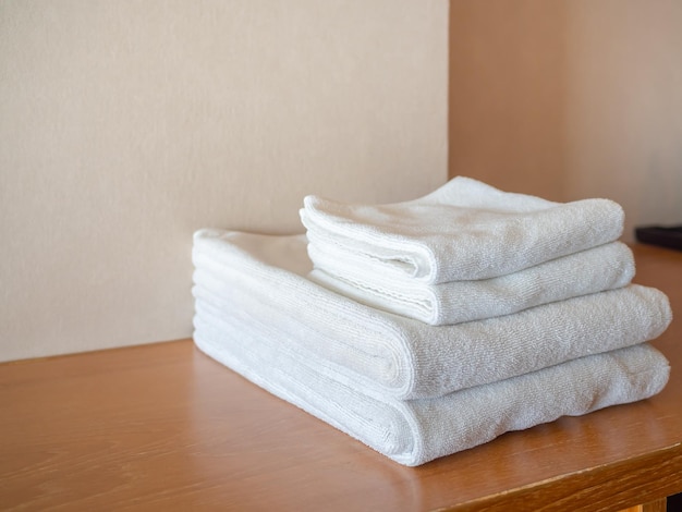 Weiße, saubere Handtücher auf Holzoberfläche und weißem Wandhintergrund