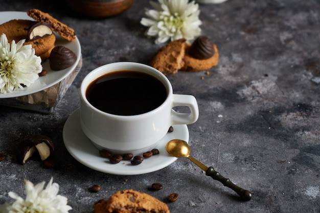 Weiße Schale schwarzer starker Kaffee mit Kaffeebohnen und Plätzchen