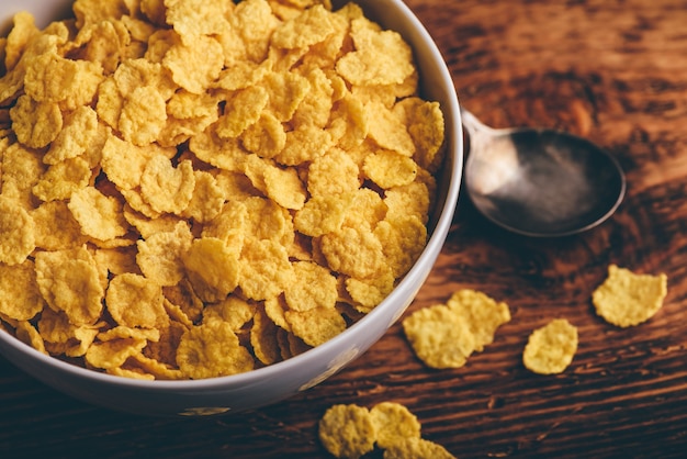 Weiße Schüssel Cornflakes auf rustikaler Holzoberfläche