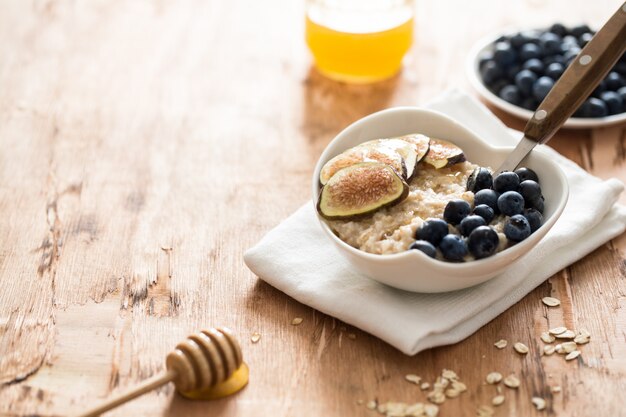 Weiße Schüssel Haferbreifeigen und -blaubeeren.