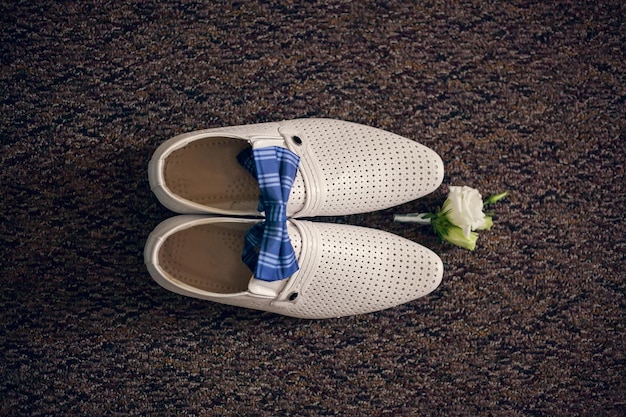 Weiße schuhe des bräutigams, fliege und boutonniere, draufsicht morgenhochzeitsdetails des bräutigams vorbereitung für die hochzeitszeremonie