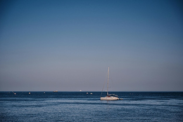 Weiße Segelyacht steht an sonnigen Sommertagen mit blauem Himmel in einer Bucht am Meer