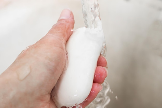 Weiße Seife in der Hand und Wasserstrahl