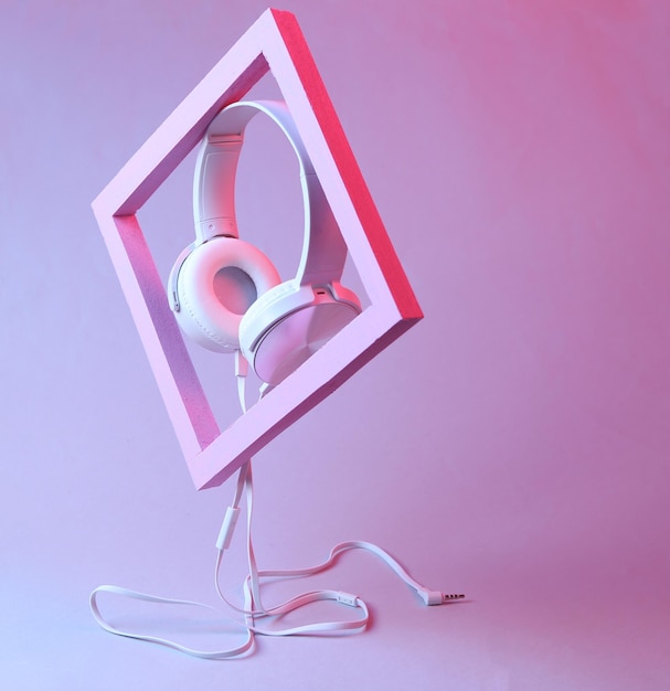 Weiße Stereokopfhörer mit rosafarbenem Rahmen in rosa blauem Neongradientenlicht Modernes minimalistisches musikalisches Stillleben