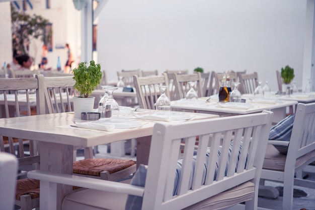 Weiße Tabellen mit Stühlen am Sommer leeren Freilichtcafé