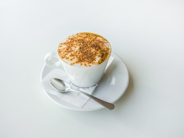 Weiße Tasse Cappuccino auf einem weißen Tisch.