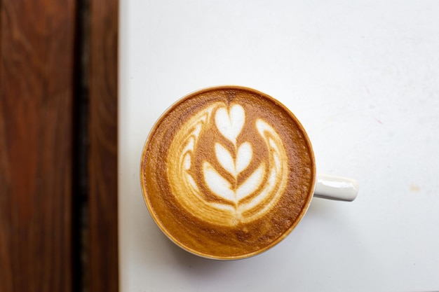Weiße Tasse Cappuccino mit Latte Art auf weißem Tisch