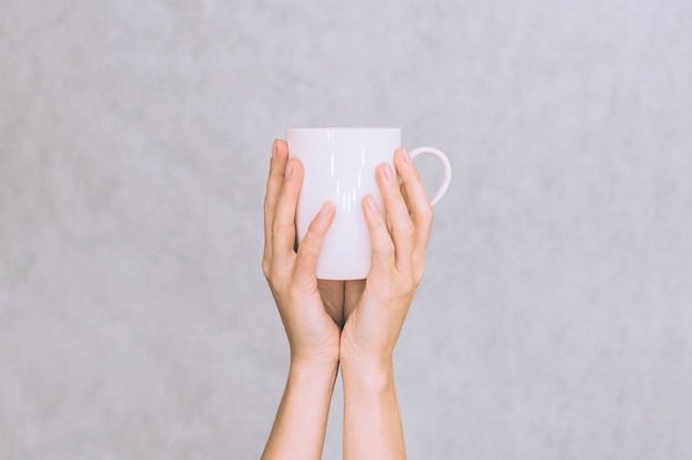 Weiße Tasse für Kaffee, Tee in den Händen eines Mädchens. Auf weißem Hintergrund.