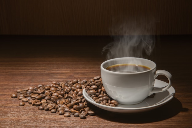 Weiße Tasse heißen Kaffee mit Rauch mit Kaffeebohnen und Sackleinen voller Kaffeebohnen mit Seil