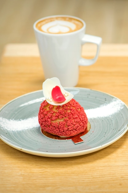 Weiße Tasse Kaffee mit Stück Kuchen in Untertasse auf dem Holztisch