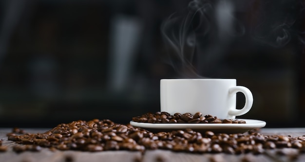 Weiße Tasse mit Espressokaffee und Körnern auf einem dunklen Holztisch