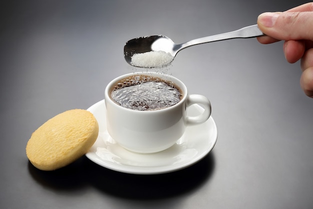 Weiße Tasse mit schwarzem Kaffee und Löffel mit Zucker