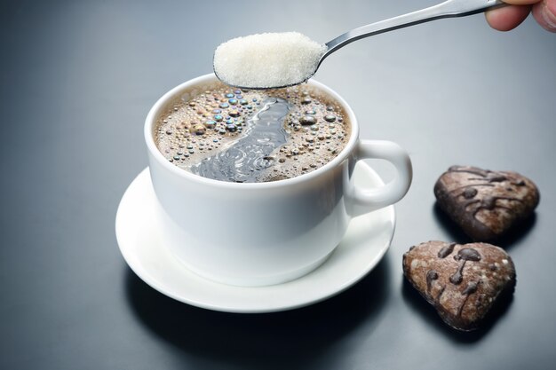 Weiße Tasse mit schwarzem Kaffee und Löffel mit Zucker