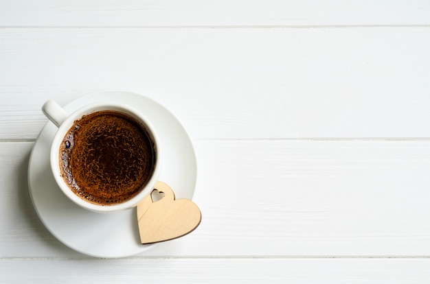 Weiße Tasse schwarzen Kaffee mit einem kleinen hölzernen Herzen auf der Seite