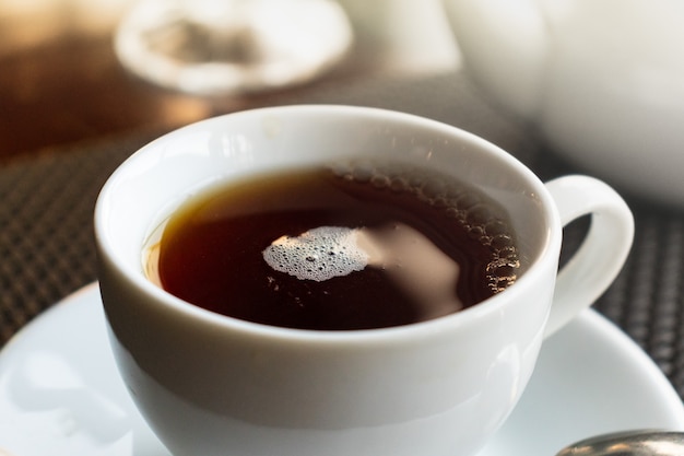 weiße Tasse Tee auf einer weißen Untertasse mit einem Löffel