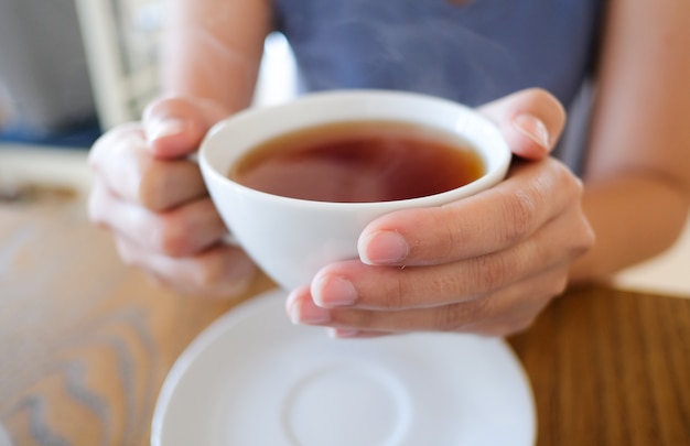 weiße Tasse Tee in der Hand