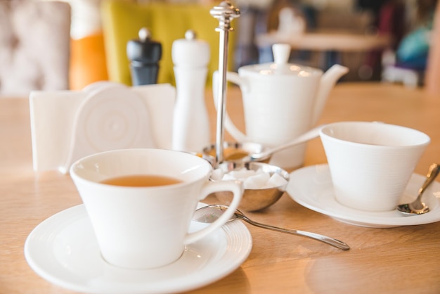 weiße Tassen mit Tee in der Nähe in Kaffeetischkeramik