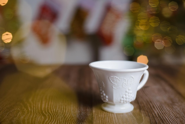 Weiße Teetasse mit geprägter Gravur auf Holztisch mit weihnachtlichem Hintergrund