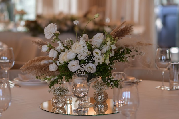Weiße Tischdecken mit klaren Vasen und weißen Chrysanthemen- und Farnarrangements