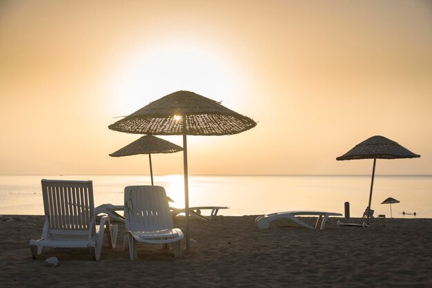 Weiße Touristenliegen am Strand an der Mittelmeerküste bei Sonnenuntergang am Mittelmeer