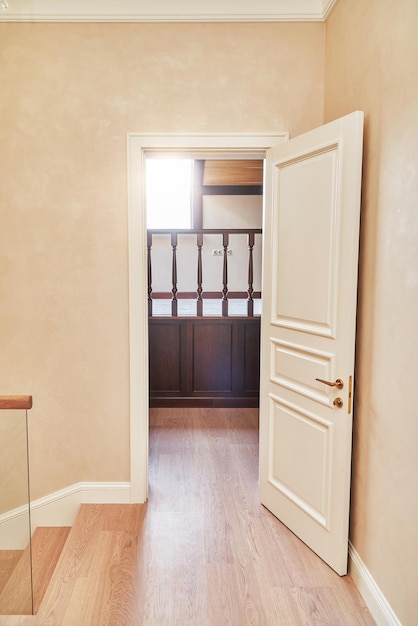 Weiße Tür im klassischen Stil mit goldenem Griff Offene Tür zur Hausbibliothek mit hölzerner Balustrade