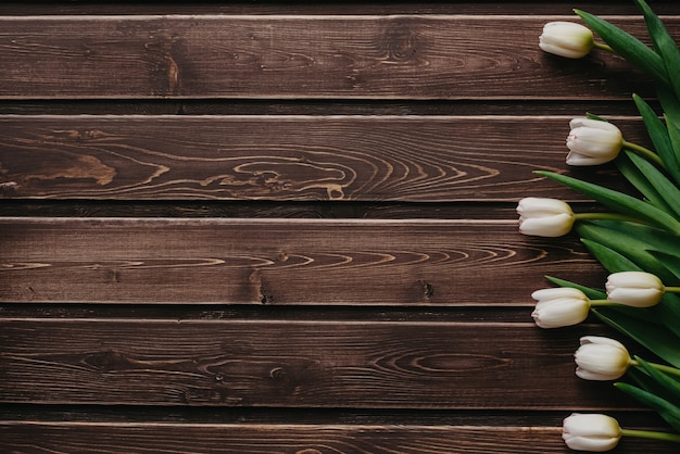 Weiße Tulpen auf einem braunen hölzernen Hintergrund. Leere Grußkarte zum Valentinstag