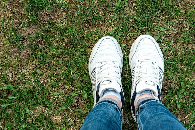 Weiße Turnschuhe auf Grashintergrund. Gesunder Lebensstil. Sport.