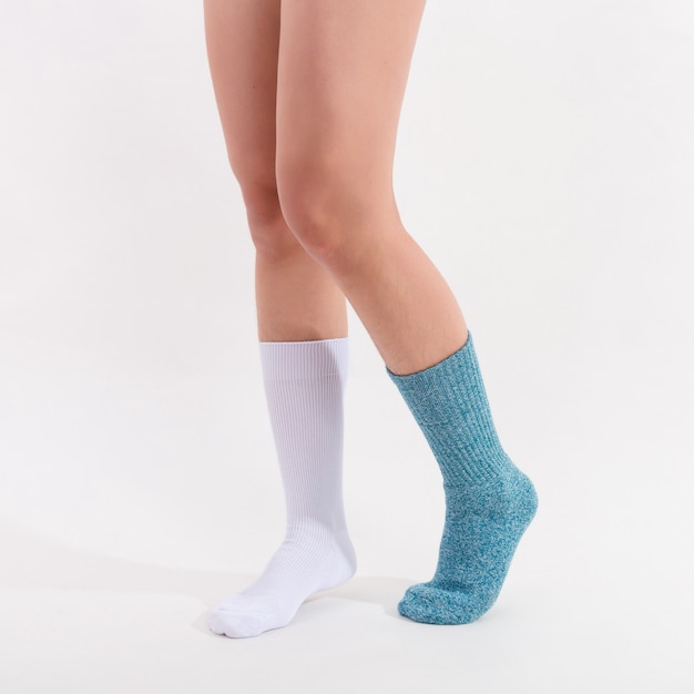 Weiße und blaue Baumwollsocken an den Füßen der schönen Frau. Isoliert auf weißem hintergrund. Studiobeleuchtung.