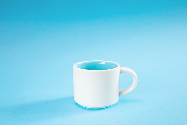 Weiße und blaue Tasse auf einem blauen Hintergrund. Minimalismus, Kopierraum.