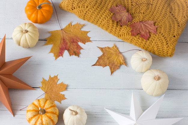 weiße und orange Kürbisse, eine gestrickte orange Decke, Herbstlaub