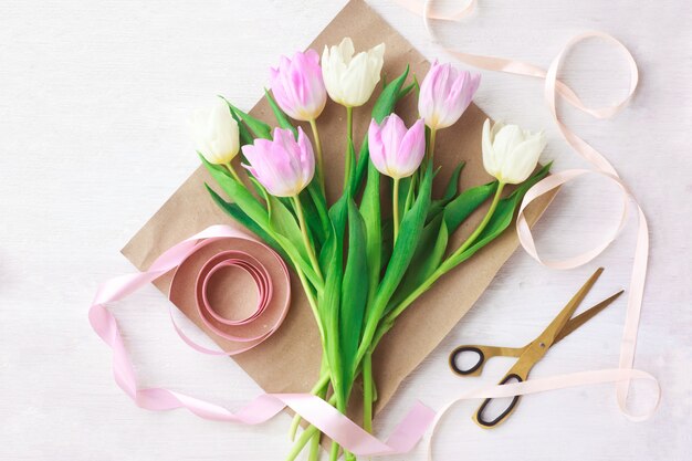 Weiße und purpurrote Tulpen auf einem weißen hölzernen Hintergrund.