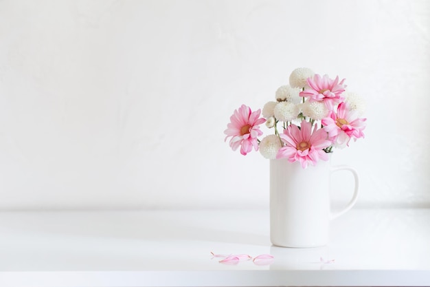 Weiße und rosa Chrysanthemen in Vintage-Cup auf weißem Hintergrund