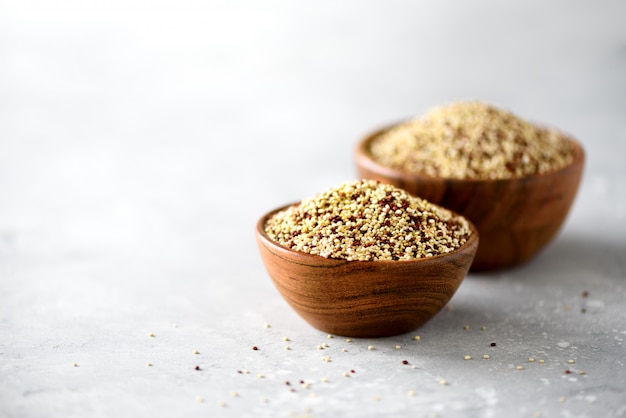 Weiße und rote rohe organische Quinoa in der hölzernen Schüssel und im Rosmarin. Gesunde Lebensmittelzutaten.