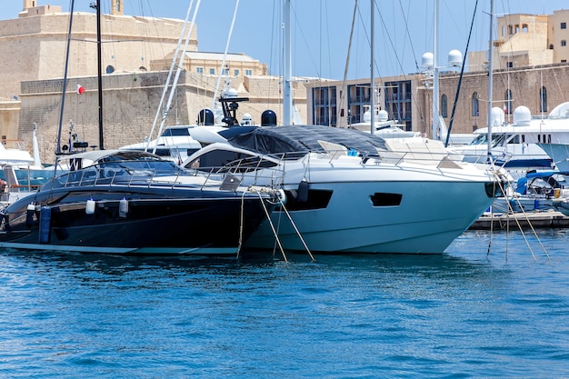 Weiße und schwarze moderne Motoryachten liegen im Hafen auf dem Stadtbildhintergrund.