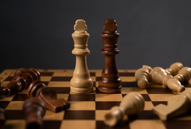 Weiße und schwarze Schachkönige stehen unter gefallenen Figuren. Zeichne auf Schachbrett.
