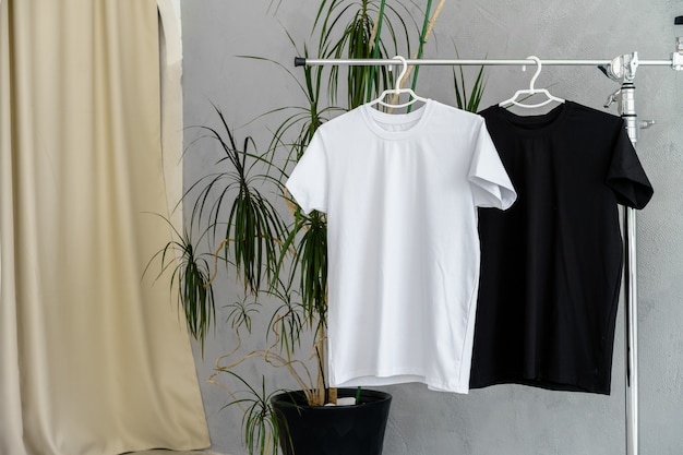 Weiße und schwarze t-shirts auf kleiderbügeln zur designpräsentation