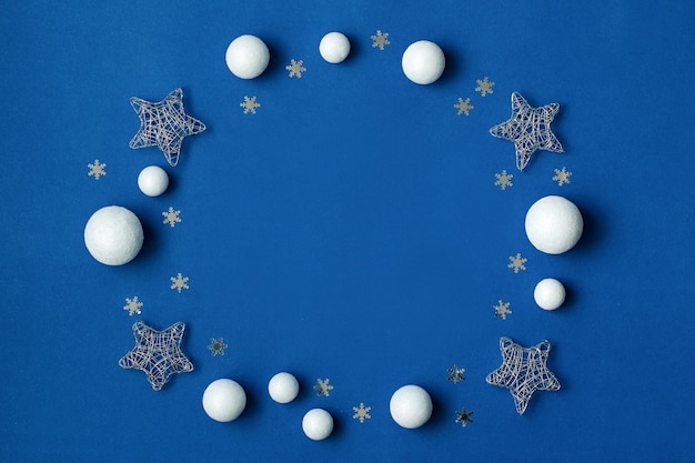 Weiße und silberne Dekorationen flach auf klassischem blauem Hintergrund mit Kopierraum. Weihnachtshintergrund in der Farbe klassisch blau mit stilvollen weißen und silbernen Ornamenten, Draufsicht